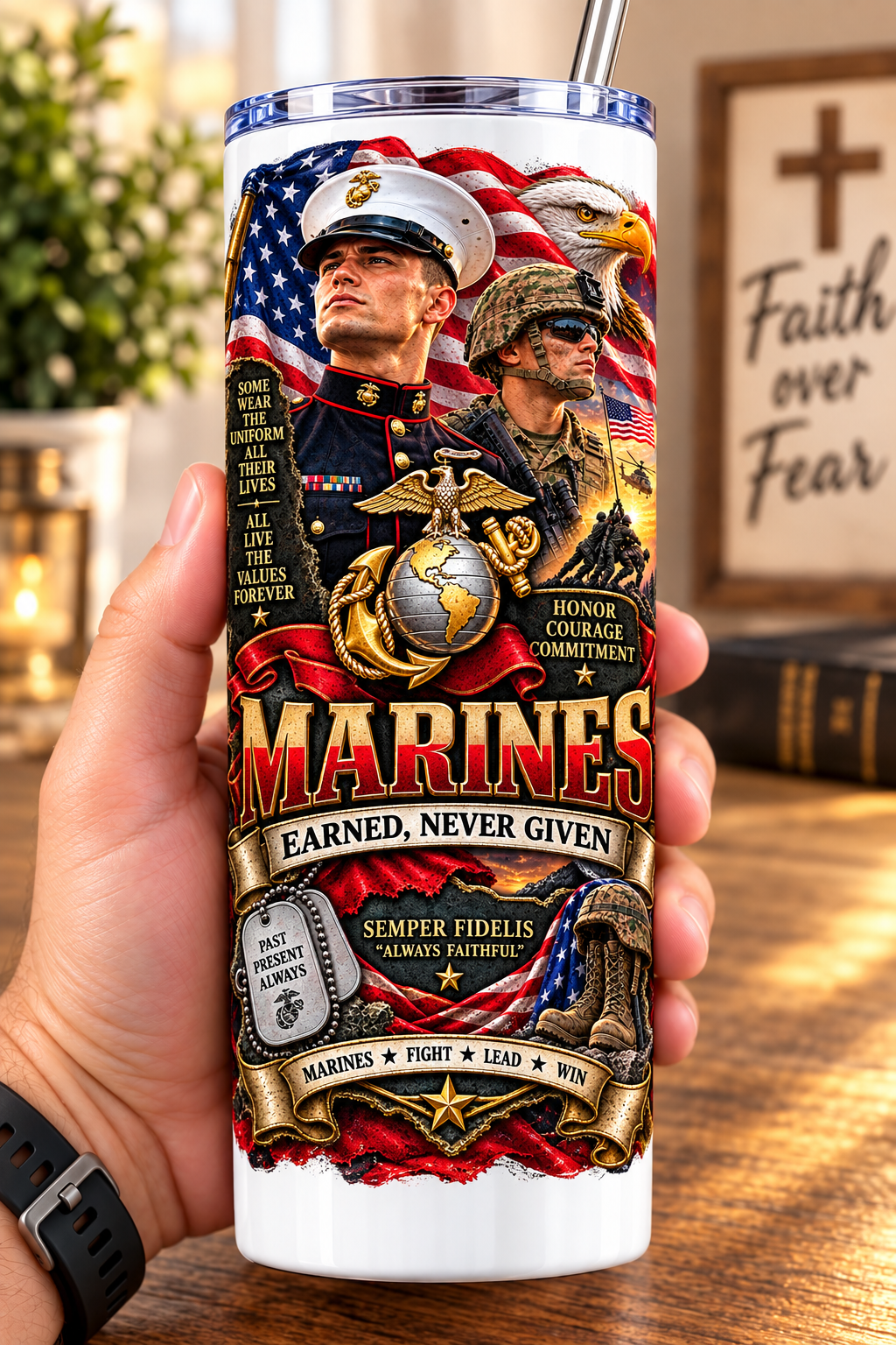 Hand holding a straight-sided 20 oz tumbler with Patriotism Marine 2 artwork on a warm wood counter