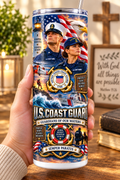 Hand holding a straight-sided 20 oz tumbler with Patriotism Coast Guard 2 artwork on a warm wood counter