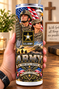 Hand holding a straight-sided 20 oz tumbler with Patriotism Army 4 artwork on a warm wood counter